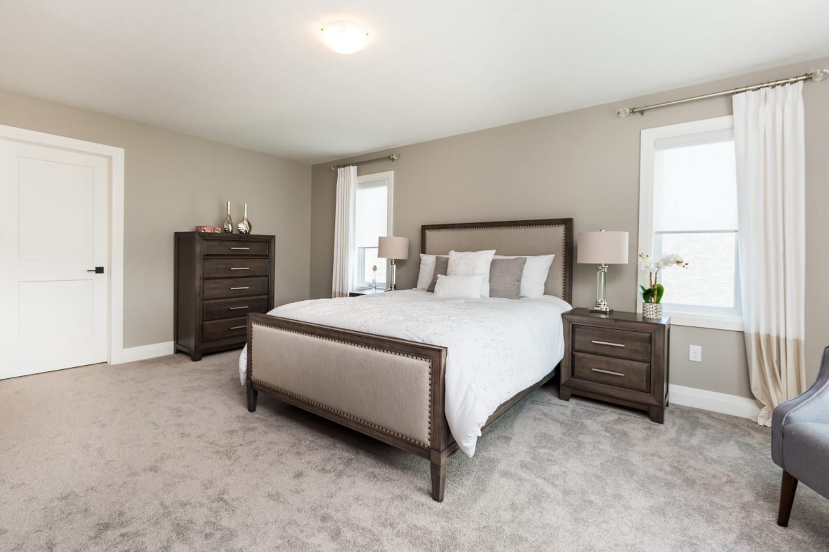 A spacious primary bedroom. Styled in inviting neutral creams and taupes.