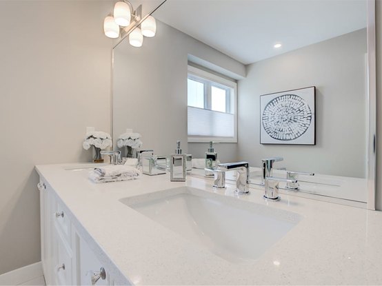 Ensuite vanity with full length mirror, designed with classic white cabinetry and chrome fixtures.