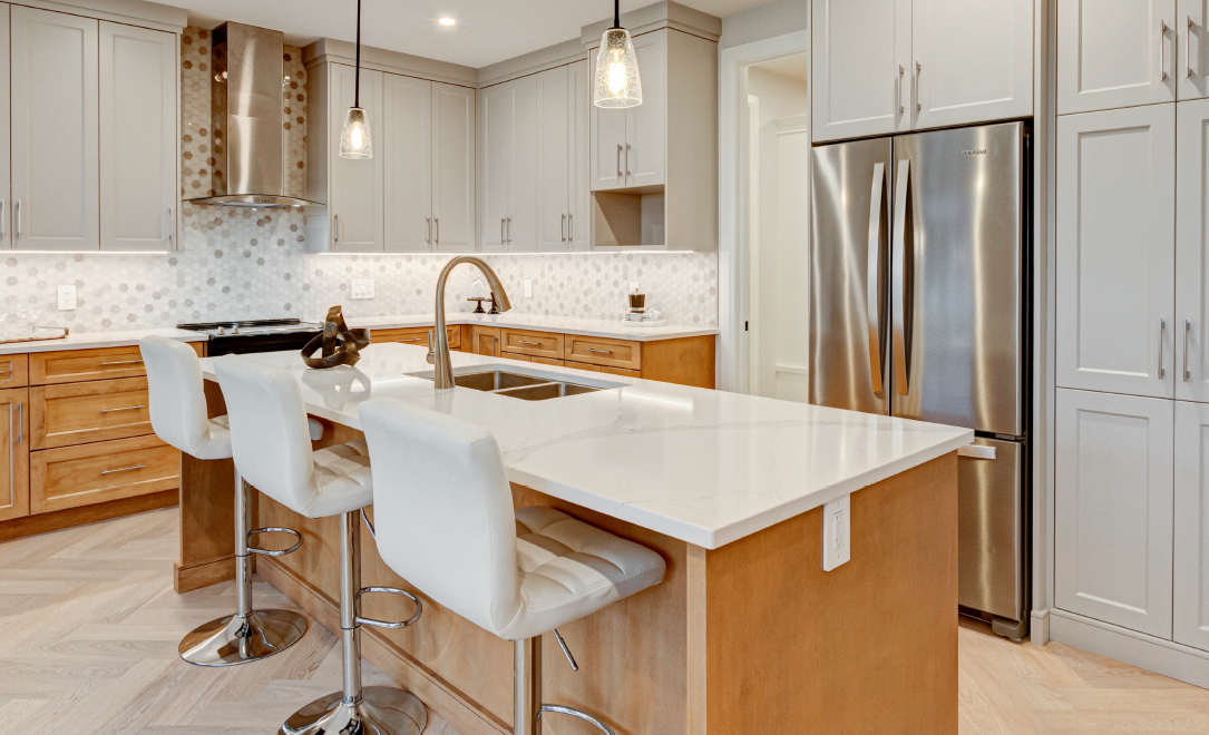 Warmly lit kitchen finished in soft white and wood cabinetry. Located at Upper West by Rembrandt Homes.